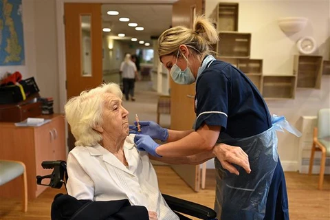 Nhân viên y tế tiêm vaccine phòng COVID-19 cho một cụ bà ở Wigan (Anh). (Ảnh: AFP/TTXVN)