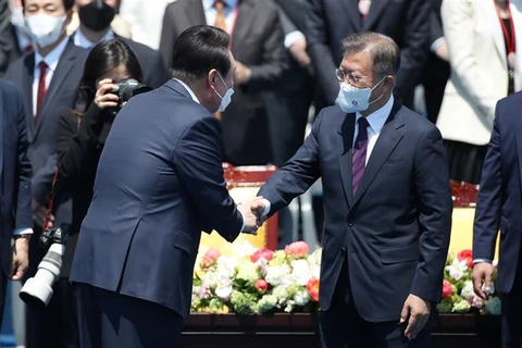 Tân Tổng thống Hàn Quốc Yoon Suk-yeol (trái) bắt tay người tiền nhiệm Moon Jae-in trong lễ nhậm chức ngày 10/5/2022. (Ảnh: TTXVN phát)