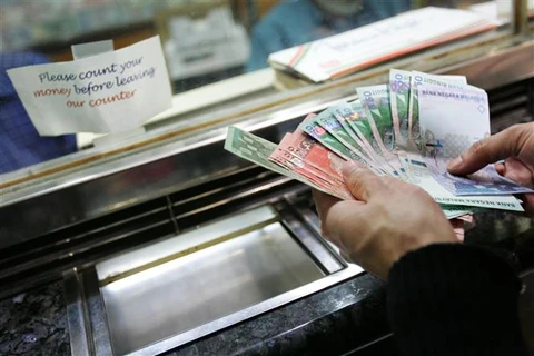 Kiểm tiền ringgit của Malaysia tại một quầy giao dịch tiền tệ ở Kuala Lumpur. (Ảnh: AFP/TTXVN)