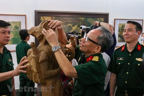 Đại tá, Anh hùng Lực lượng vũ trang nhân dân Lê Duy Ứng với tác phẩm điêu khắc “Bài ca người mẹ.” (Ảnh: Minh Hiếu/Vietnam+)