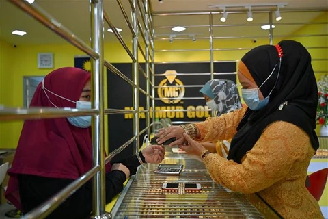 Khách hàng chọn mua đồ trang sức vàng tại tiệm kim hoàn ở Kota Bharu (Malaysia). (Ảnh: AFP/TTXVN)