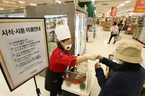 Nhân viên giới thiệu đồ ăn cho khách tại một siêu thị ở Seoul (Hàn Quốc) ngày 25/4/2022, khi hoạt động ăn uống được phép nối lại tại đây. (Ảnh: Yonhap/TTXVN)