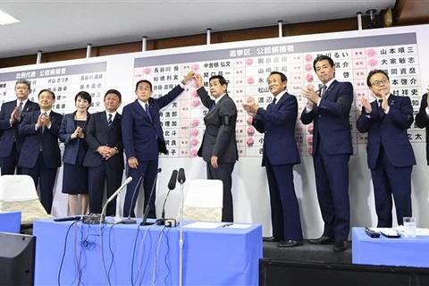 Thủ tướng Nhật Bản Kishida Fumio (giữa, trái) gắn hoa hồng bên cạnh tên của các ứng cử viên trúng cử trong cuộc bầu cử Thượng viện, tại Tokyo ngày 10/7/2022. (Ảnh: AFP/TTXVN)