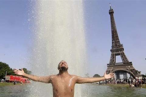 Người dân giải nhiệt tránh nắng nóng tại một đài phun nước ở Paris (Pháp), ngày 18/6/2022. (Ảnh: AFP/TTXVN)
