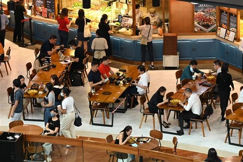 Người dân dùng bữa tại một nhà hàng trong trung tâm thương mại ở Singapore. (Ảnh: AFP/TTXVN)