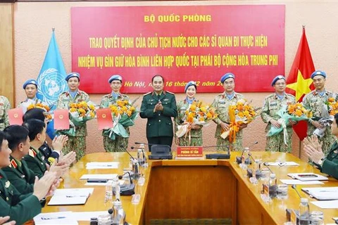 Thượng tướng Phùng Sĩ Tấn trao quyết định cho bốn sỹ quan và chúc mừng bốn sỹ quan đã hoàn thành nhiệm vụ. (Ảnh: Trọng Đức/TTXVN)