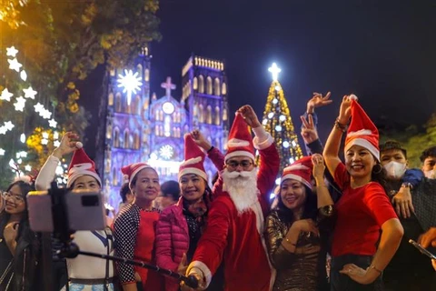 Người dân Thủ đô hào hứng chụp ảnh lưu niệm trong không khí đón Giáng sinh trước Nhà thờ Lớn. (Ảnh: Tuấn Đức/TTXVN)