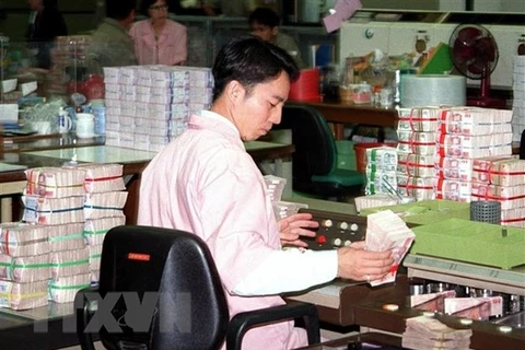 Nhân viên kiểm tra những cọc tiền baht Thai tại ngân hàng trung ương ở Bangkok, Thái Lan. (Ảnh: AFP/TTXVN) 