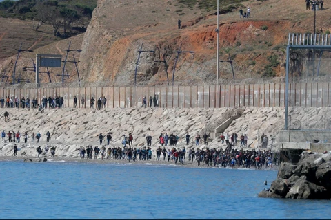 Người di cư chạy về phía hàng rào ngăn cách Maroc với Tây Ban Nha, sau khi hàng nghìn người di cư bơi qua biên giới, ở Ceuta (Tây Ban Nha), ngày 19/5/2021. (Nguồn: Reuters/Ảnh chụp màn hình)