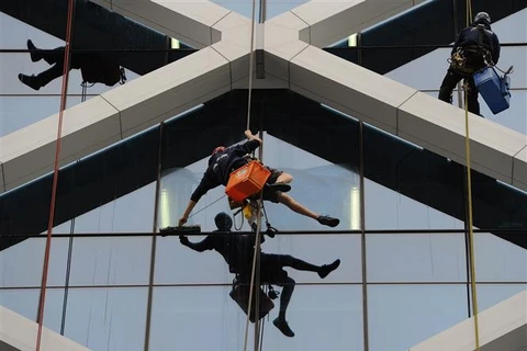 Công nhân lau kính tại tòa nhà cao tầng ở Sydney (Australia). (Ảnh minh họa: AFP/TTXVN)