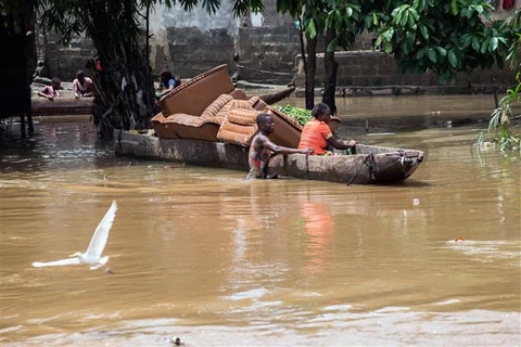 Người dân di chuyển bằng thuyền trên đường phố ngập lụt do mưa lớn tại Kinshasa (Cộng hòa Dân chủ Congo). (Ảnh: AFP/TTXVN)