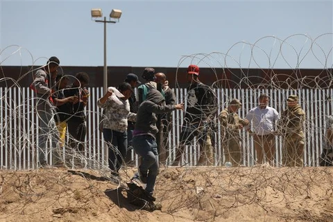 Người di cư vượt qua hàng rào biên giới Mỹ-Mexico ở Texas (Mỹ), ngày 8/5/2023. (Ảnh: AFP/TTXVN)