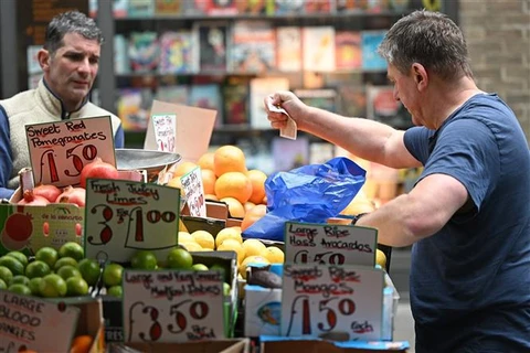 Người dân mua hàng tại một chợ ở London (Anh). (Ảnh: AFP/TTXVN)