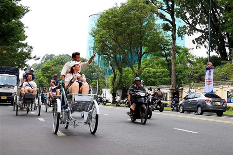 Du khách quốc tế tham quan trung tâm Thành phố Hồ Chí Minh bằng xích lô. (Ảnh: Hồng Đạt/TTXVN)