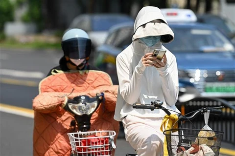 Người dân mặc áo chống nắng bảo vệ trong thời tiết nắng nóng gay gắt tại Thượng Hải (Trung Quốc), ngày 29/5/2023. (Ảnh: AFP/TTXVN)