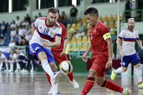 Pha tranh bóng giữa các tuyển thủ Việt Nam (áo đỏ) với cầu thủ Nga. (Ảnh: Thanh Vũ/TTXVN)