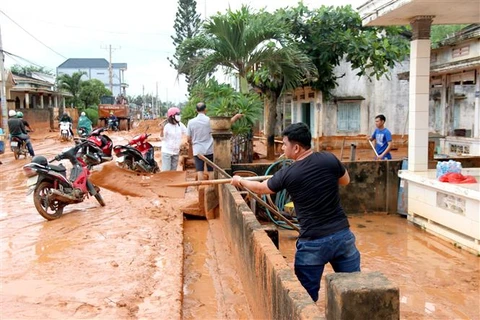 Đến trưa 2/10, người dân tại thôn Tiến Phú, xã Tiến Thành, thành phố Phan Thiết, vẫn khẩn trương dọn dẹp cát đỏ tràn vào nhà. (Ảnh: Nguyễn Thanh/TTXVN)