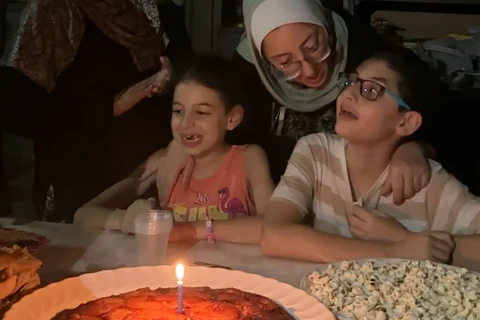 Hashem mừng sinh nhật thứ 12 của mình với chiếc bánh dứa yêu thích, cùng với mẹ Hiba và em gái Basma. (Nguồn: CNN/Ảnh chụp màn hình)