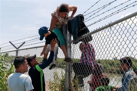 Người di cư trèo qua hàng rào từ Mexico vào Mỹ tại Eagle Pass, bang Texas (Mỹ) ngày 25/8/2023. (Ảnh: AFP/TTXVN)