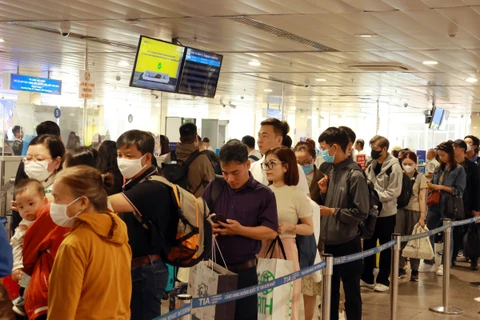 Hành khách xếp hàng làm thủ tục soi chiếu kiểm tra an ninh tại sân bay Tân Sơn Nhất. (Ảnh: Quang Châu/TTXVN)