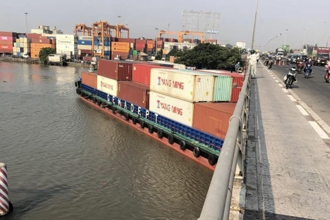 Tàu Phước Long 72 chở container số hiệu SG9838 trọng tải 4.600 tấn bị mắc kẹt dưới cầu Đồng Nai sáng 12/4, trước khi được cứu hộ và lai dắt đến nơi an toàn. (Ảnh: TTXVN phát)