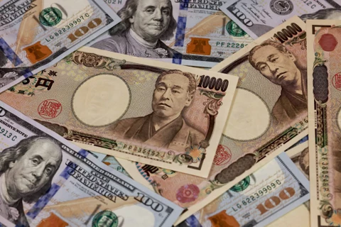 Đồng tiền mệnh giá 10.000 yen và 100 USD. (Ảnh: AFP/TTXVN)