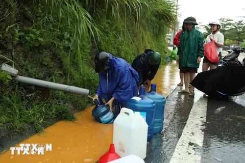 Người dân thành phố Lào Cai vất vả để lấy được đầy can nước được chảy ra từ khe núi. (Ảnh: Quốc Khánh/TTXVN)