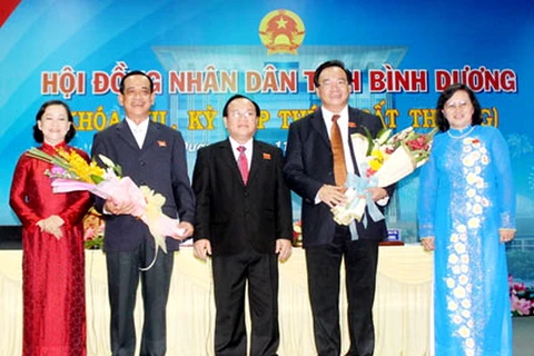 Hai ông Phạm Văn Cành (thứ hai từ trái qua) và Vũ Minh Sang (thứ hai từ phải qua) nhận hoa chúc mừng của lãnh đạo tỉnh Bình Dương. (Nguồn: binhduong.gov.vn)