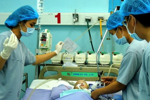 Các bác sỹ kiểm tra tình trạng sức khỏe của bé Nguyễn Hoàng Phi Long sau phẫu thuật. (Ảnh: Hứa Chung/TTXVN)