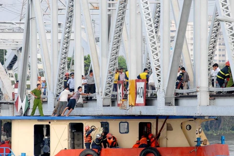 Lực lượng cứu hộ khẩn trương giải thoát sà lan khỏi gầm cầu Bình Lợi trong điều kiện thủy triều dâng cao. (Ảnh: Mạnh Linh/TTXVN)