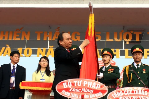 Phó thủ tướng Nguyễn Xuân Phúc gắn Huân chương Độc lập hạng Nhì lên lá cờ truyền thống tỉnh Hậu Giang. (Ảnh: Duy Khương/TTXVN)