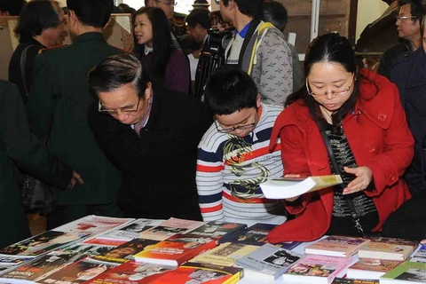 Khách tham quan triển lãm nghệ thuật tổng hợp tôn vinh Đại tướng Võ Nguyên Giáp, xem các ấn phẩm viết về Đại tướng. (Nguồn: TTXVN)