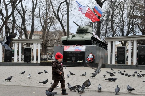 Một cậu bé chơi đùa trước tượng đài xe tăng T-34 ở Simferopol, Crimea. (Nguồn: AFP)