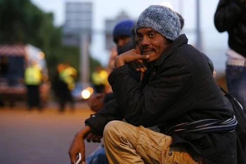Một người nhập cư ngồi trước cổng vào đường hầm Channel ở Pháp. (Nguồn: Reuters)