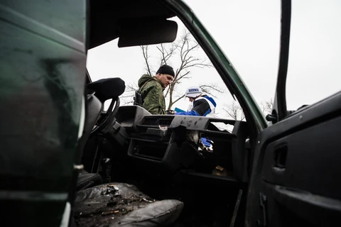Một lính phe ly khai và một quan sát viên quốc tê của tổ chức OSCE đứng bên cạnh một chiếc xe bị phá hủy bởi đạn pháo gần làng Shirokino. (Nguồn: AFP)