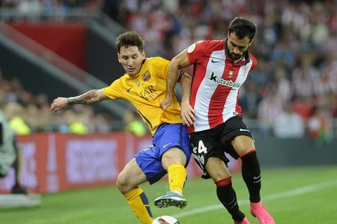 Tiền đạo Lionel Messi (trái) tranh bóng với hậu vệ của Athletic Bilbao, Mikel Balenziaga (phải) trân trận lượt đi Siêu cúp Tây Ban Nha. (Nguồn: AFP)