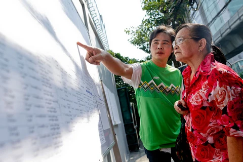 Hai công dân Myanmar tìm tên của họ trong bảng danh sách cử tri tại điểm bỏ phiếu ở Đại sứ quán Myanmar ở Bangkok, Thái Lan. (Nguồn: EPA) 