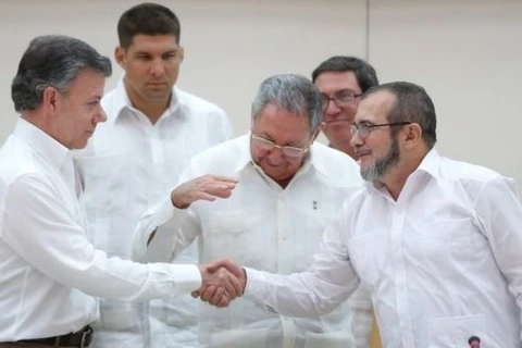 Tổng thống Colombia Juan Manuel Santos (trái) bắt tay thủ lĩnh FARC Timochenko (phải) dưới sự chứng kiến của Chủ tịch Cuba Raul Castrotại vòng đàm phán hòa bình ở Cuba, tháng trước. (Nguồn: Reuters) 