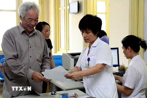 Nhân viên y tế Bệnh viện Bạch Mai hướng dẫn người khám chữa bệnh giải quyết thủ tục. (Ảnh: Dương Ngọc/TTXVN)