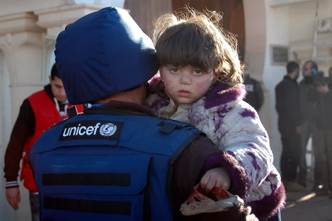 Một nhân viên UNICEF bế một bé gái ở Homs, Syria. (Nguồn: EPA)