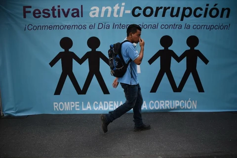 Một thanh niên đi qua một tấm panô tuyên truyền chống tham nhũng ở Guatemala City. (Nguồn: AFP)