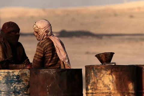 Hai người đàn ông đứng bên cạnh các thùng phuy đựng dầu thô ở Raqqa, Syria. (Nguồn: Reuters)