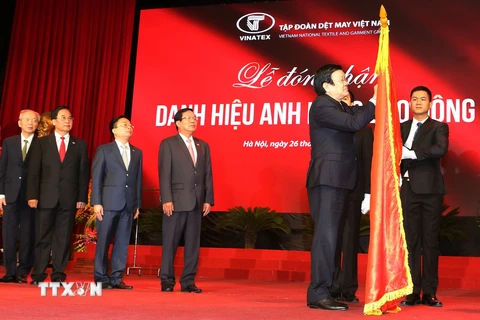 Chủ tịch nước Trương Tấn Sang gắn danh hiệu Anh hùng Lao động lên lá cờ truyền thống của Tập đoàn Dệt may Việt Nam. (Ảnh: Nguyễn Khang/TTXVN) 