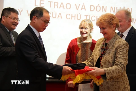 Đại sứ Việt Nam tại Pháp Nguyễn Ngọc Sơn đón nhận chiếc mũ dạ từ bà Claire Biquard (con gái ông Pierre Biquard). (Ảnh : Bích Hà/TTXVN) 