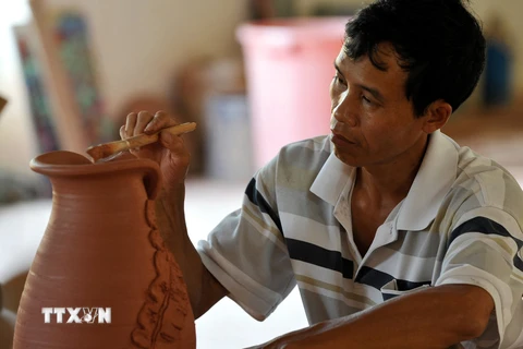 Người thợ gốm Phù Lãng tạo hoa văn cho sản phẩm. (Ảnh: Thanh Hà/TTXVN)