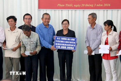 Ông Trương Hòa Bình, Chánh án Tòa án Nhân dân tối cao tặng tiền hỗ trợ cho đồng bào vùng hạn hán. (Ảnh: Nguyễn Thanh/TTXVN)