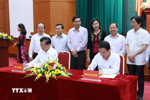 Bộ trưởng Bộ Tài chính Đinh Tiến Dũng (bên trái) và Tổng giám đốc TTXVN Nguyễn Đức Lợi ký văn kiện phối hợp tuyên truyền. (Ảnh: Hoàng Hùng/TTXVN)