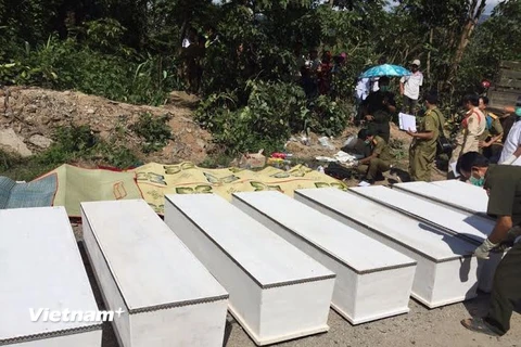 Lực lượng chức năng khẩn trương làm các thủ tục để chuyển thi thể các nạn nhân khỏi hiện trường. (Ảnh: Nguyễn Chiến/Vietnam+)