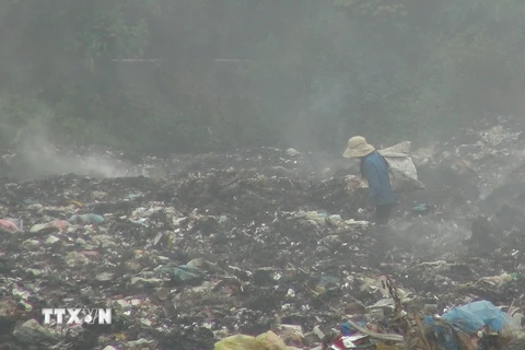Rác vẫn âm ỉ cháy tại bãi rác xã Trường Thủy khiến khói bụi mù mịt. (Ảnh: Đức Thọ/TTXVN)