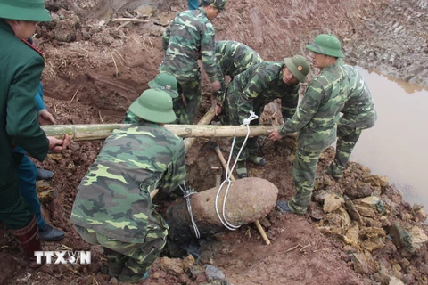 Lực lượng công binh tiến hành trục vớt quả bom nằm sâu dưới lòng đất. (Ảnh: Mai Ngoan/TTXVN)
